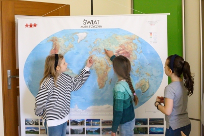 Uczniowie przyglądaja się mapie fizycznej świata.