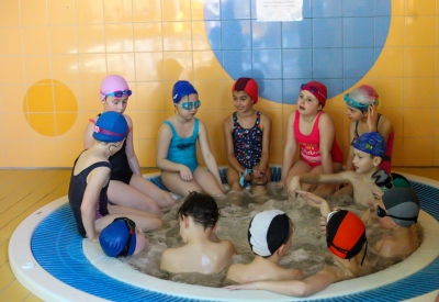 Grupa uczniów po zajęciach na basenie odpoczywa i relaksuje się w jacuzzi.