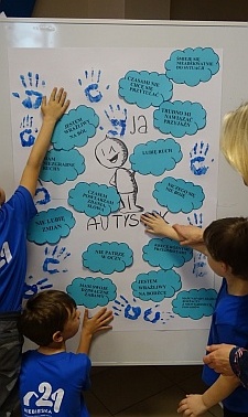Uczniowie odciskają swoje dłonie na kolażu na znak solidarności z osobami z spectrum autyzmu.
